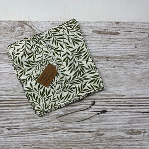 May include: A stack of green and white fabric squares with a tag that reads "Liberty of London Willow Boughs".