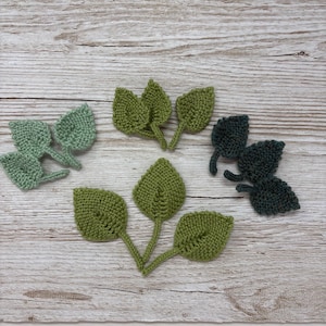 May include: Five sets of knitted leaves in various shades of green. Each set is made of three leaves connected at the base.