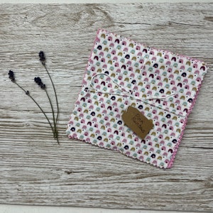 May include: A set of four pink fabric squares with a white background and a pattern of small, colourful rainbows. The squares are tied together with twine and a brown tag that reads "Pink Rainbows".