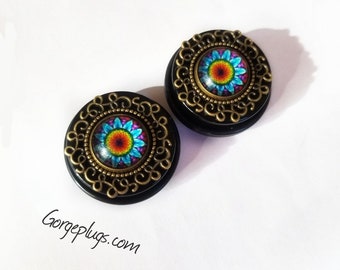 May include: Pair of black wood ear gauges with a gold metal filigree design and a colorful flower inlay.