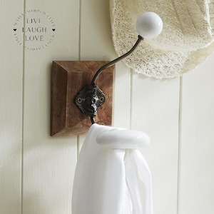 May include: A wall-mounted coat hook with a wooden base and a metal hook. The hook features a white ceramic knob and a white scarf. The text "LIVE LAUGH LOVE" is printed on the wall.