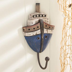 May include: A blue and white wooden ship-shaped wall hook with a metal hook. The ship has a distressed paint finish and is decorated with brown and red accents.