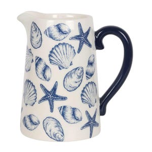 May include: A white ceramic jug with a navy blue handle and spout. The jug is decorated with blue illustrations of seashells and starfish. The jug is a decorative item for the kitchen or dining room.
