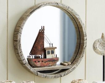May include: A round wooden mirror with a rustic finish, featuring a small wooden sailboat with red and white paint, and a weathered look, in the reflection. The mirror is surrounded by a thick wooden frame with a rope-like design.