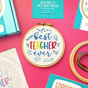 May include: A DIY embroidery kit with a white hoop featuring the text "best teacher ever" in rainbow colours. The hoop is surrounded by colourful embroidery floss and a needle.