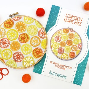 May include: A lemon slice embroidery kit with pre-printed fabric and a stitch guide. The kit includes a hoop with a white fabric background and a pattern of yellow and orange lemon slices. The packaging is teal with white polka dots and the text "Embroidery Fabric Pack" and "Oh Sew Bootiful".