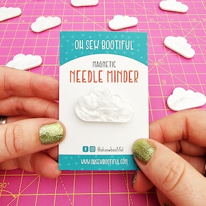 May include: White cloud-shaped magnetic needle minder with the text "Oh Sew Bootiful" and "Magnetic Needle Minder" on a white card with blue and green accents.