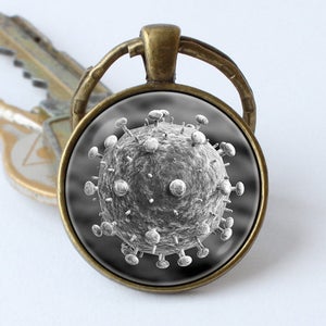 May include: A bronze key chain with a round glass charm featuring a black and white microscopic image of a virus.