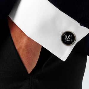 May include: Black cufflinks with a silver finish and a round black face with the text "0.6" (1.6cm) printed in white.
