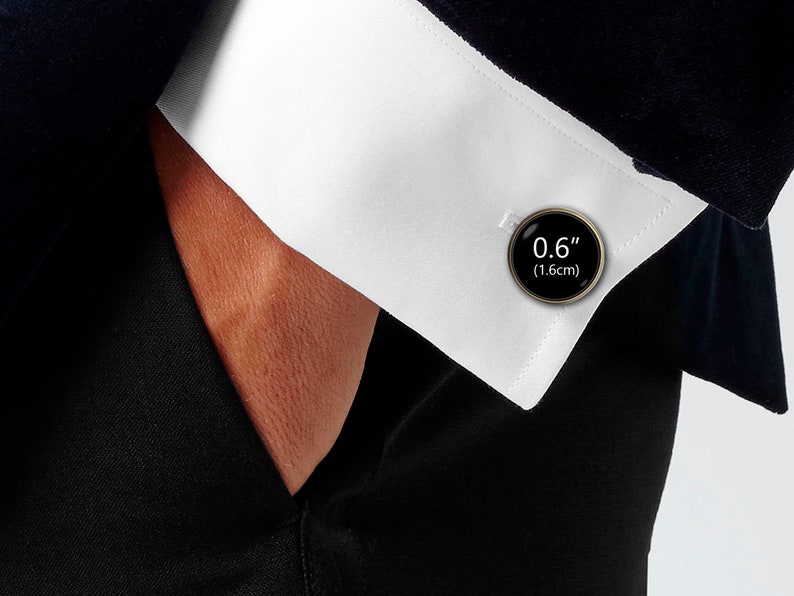 May include: Black cufflinks with a silver finish and a round black face with the text "0.6" (1.6cm) printed in white.