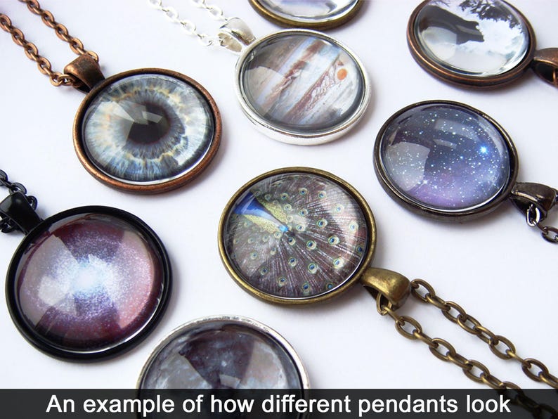 May include: A collection of different pendants with various designs, including an eye, a peacock feather, a galaxy, and a planet. The pendants are made of glass and are set in metal frames. The pendants are all on chains.