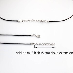 May include: Black cord necklace with a silver chain extension. The extension is 2 inches (5 cm) long. Additional 2 inch (5 cm) chain extension.