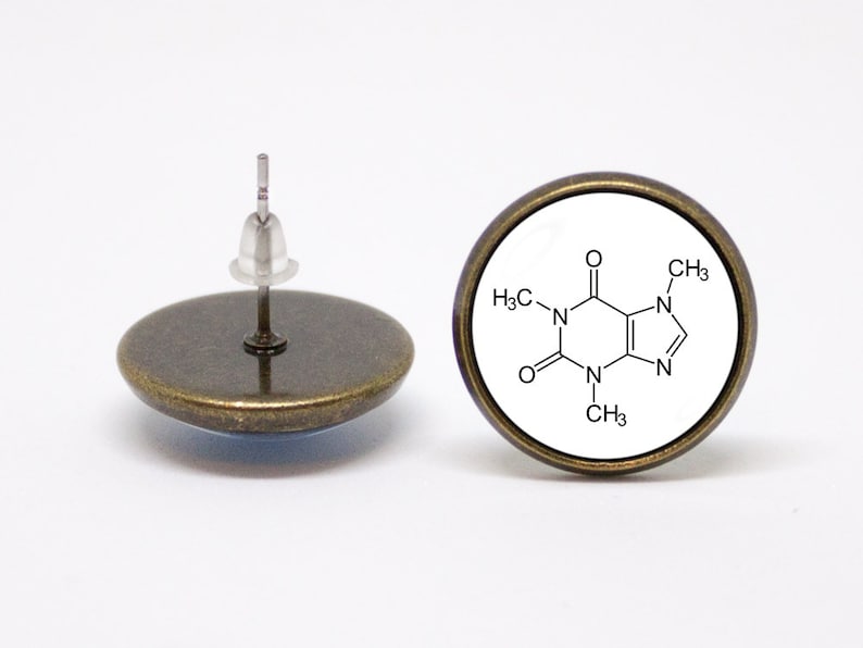 May include: A pair of bronze-coloured stud earrings with a white background and a chemical structure of caffeine printed on them.