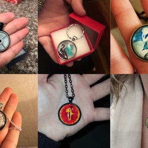 May include: A set of five different glass cabochon pendants with various designs. The pendants are on necklaces and keychains. The designs include a weight plate, a compass, a pair of swans, an eye, and a mermaid.