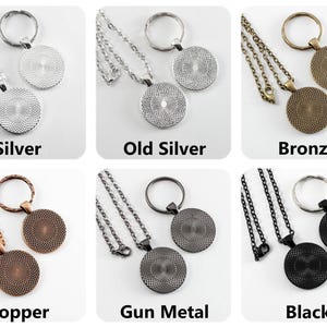 May include: Six different color variations of a necklace and keychain set. The set includes a silver, old silver, bronze, copper, gun metal, and black chain with a round pendant. Each chain has a matching key ring.