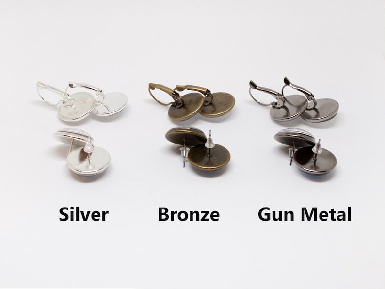 May include: Three pairs of earrings with different metal finishes: silver, bronze, and gunmetal. Each pair features a round, glass cabochon.