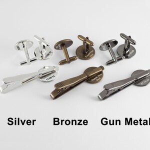 Puede incluir: Tres juegos de gemelos y clips de corbata en plata, bronce y metal gris. Cada juego presenta una placa redonda grabada con una fecha diferente.