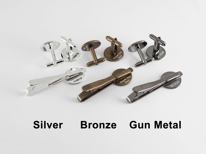 Puede incluir: Tres juegos de gemelos y clips de corbata en plata, bronce y metal gris. Cada juego presenta una placa redonda grabada con una fecha diferente.