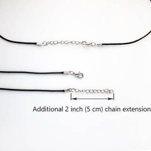 May include: Two black leather cords with silver clasps and a 2 inch (5 cm) chain extension.  Additional 2 inch (5 cm) chain extension.