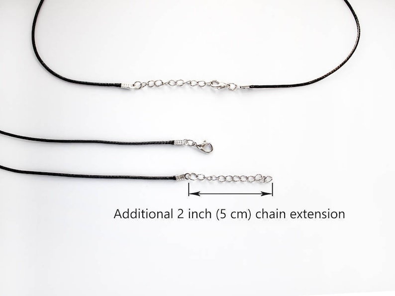 May include: Two black leather cords with silver clasps and a 2 inch (5 cm) chain extension.  Additional 2 inch (5 cm) chain extension.
