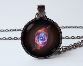 May include: A black chain necklace with a round pendant featuring a colorful image of the Hourglass Nebula. The pendant is made of glass and has a silver-toned metal frame.