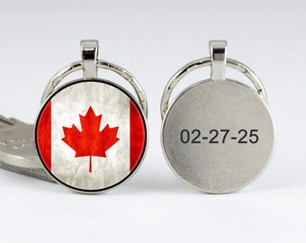 May include: A silver key chain with a round charm featuring the Canadian flag and a second round charm with the text "02-27-25".