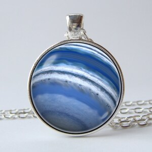 May include: A silver necklace with a round pendant featuring a blue and white agate stone. The pendant has a silver bezel setting.