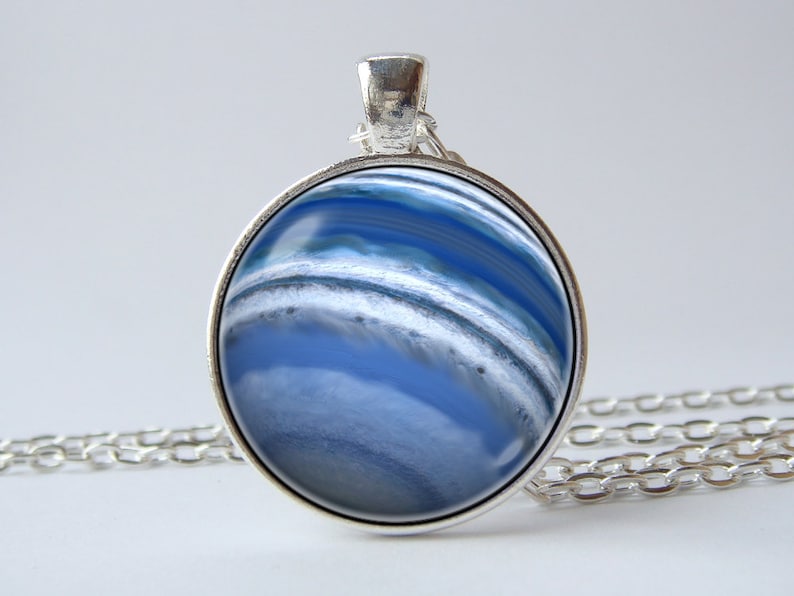 May include: A silver necklace with a round pendant featuring a blue and white agate stone. The pendant has a silver bezel setting.