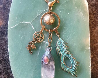 May include: A bronze-toned keychain with a clear crystal pendant, a turquoise feather charm, and other mystical charms. The keychain includes a pentagram, a small dragon, and a decorative sphere. The crystal is clear with a pinkish top.
