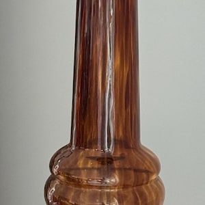 May include: A brown glass table lamp with a gold metal base and a gold metal socket. The lamp has a unique, swirled design.