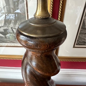 May include: A dark brown wooden lamp base with a twisted design and a gold metal top.
