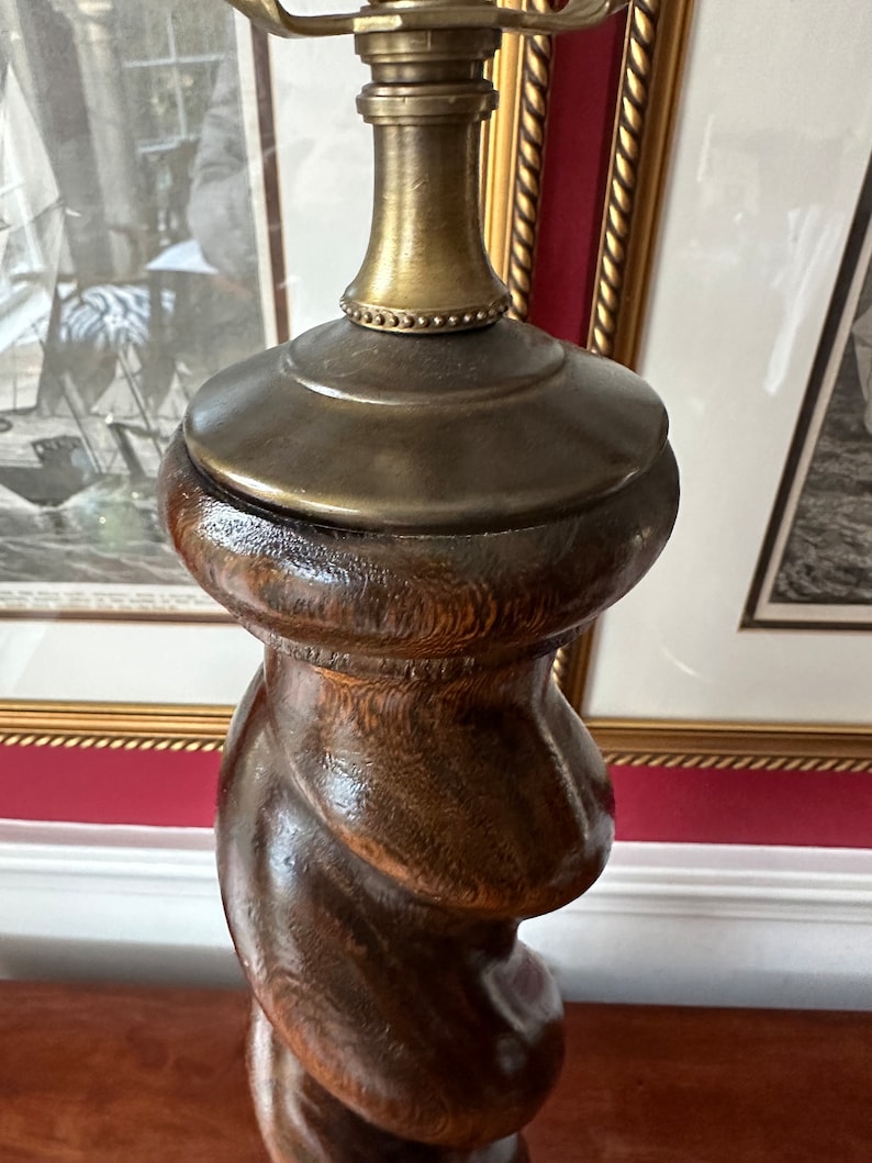 May include: A dark brown wooden lamp base with a twisted design and a gold metal top.