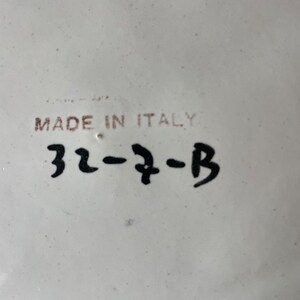 K&ouml;nnte beinhalten: Wei&szlig;e Keramikplatte mit schwarzem Text, der "Made in Italy" und "32-7-B" lautet.