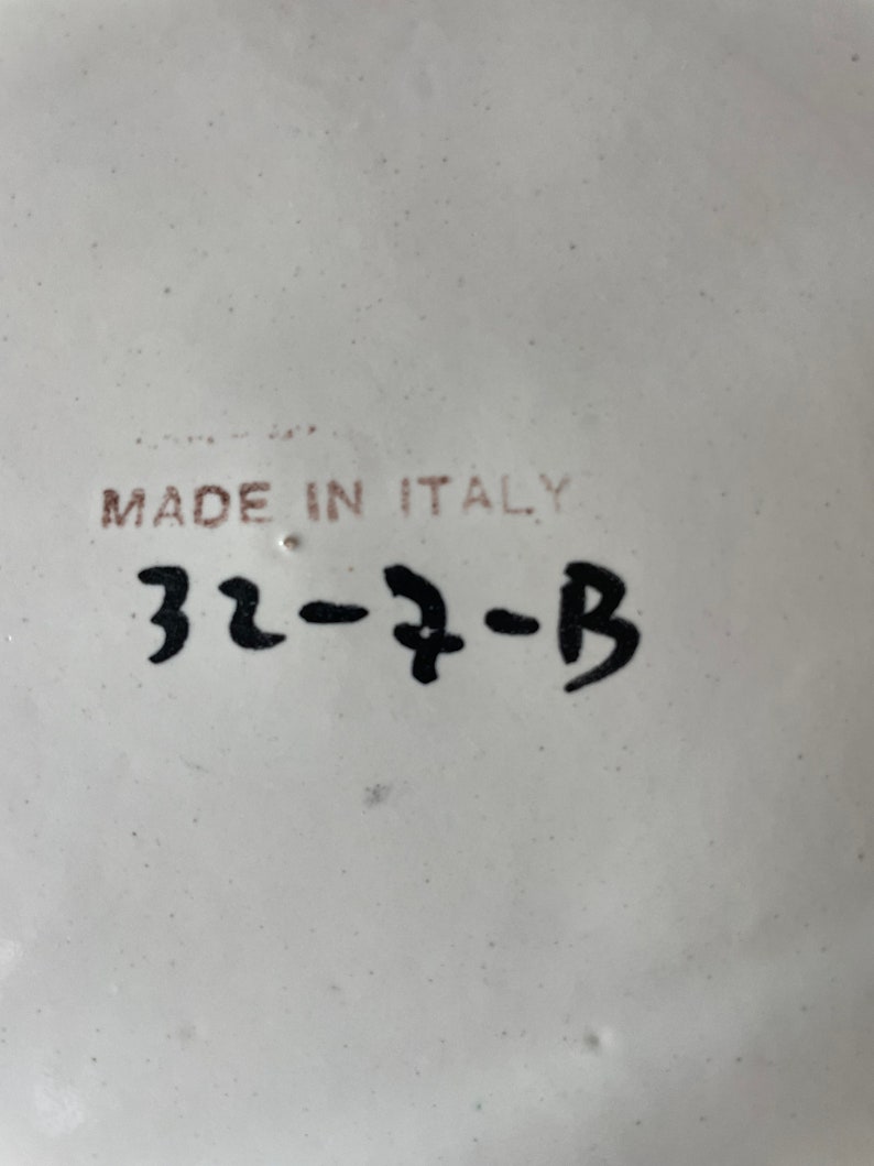 K&ouml;nnte beinhalten: Wei&szlig;e Keramikplatte mit schwarzem Text, der "Made in Italy" und "32-7-B" lautet.