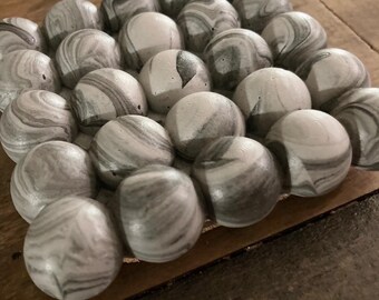 May include: A square coaster made of concrete with a marbled design in shades of gray and white. The coaster is made up of 36 individual spheres.