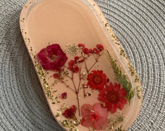May include: A pink oval resin tray with pressed red and pink flowers and gold leaf accents.