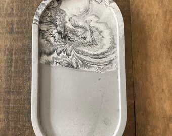 May include: A gray and white oval-shaped concrete tray with a marbled design. The tray has a smooth, slightly textured surface.