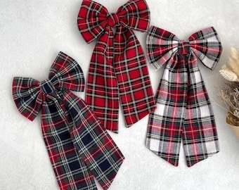 Puede incluir: Tres lazos para el pelo de cuadros rojos y blancos con forma de lazo y colas largas. Los lazos están hechos de tela y tienen un patrón a cuadros.