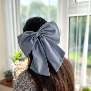 May include: A large, light blue satin bow tied at the back of a person's hair.
