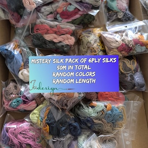 Könnte beinhalten: Eine Schachtel voller klarer Plastiktüten mit farbenfrohem Stickgarn. Die Beutel enthalten verschiedene Schattierungen von Rosa, Blau, Grün und neutralen Tönen. Text auf blauem und violettem Hintergrund lautet "MISTERY SILK PACK OF 6PLY SILKS 50M IN TOTAL RANDOM COLORS RANDOM LENGTH."