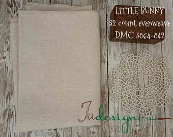 Peut inclure: Un tissu en lin beige avec un petit motif de point de croix dans le coin inférieur droit. Le tissu est étiqueté "LITTLE BUNNY 32 count evenweave DMC 3864-842".