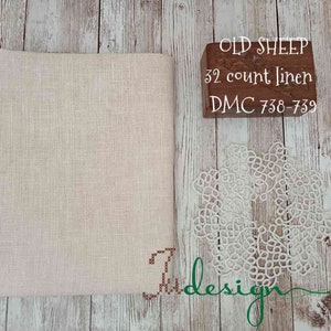 May include: A piece of off-white linen fabric with a brown wooden block that reads "OLD SHEEP 32 count linen DMC 738-739".
