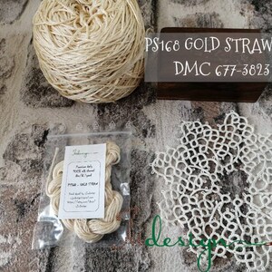 Puede incluir: Una madeja de hilo de seda de paja dorada, etiquetada como "PS168 GOLD STRAW silk DMC 677-3823". El hilo está en una bolsa de plástico transparente con una etiqueta que dice "Premium baby  silk thread DMC 677-3823 PS168 - GOLD STRAW".
