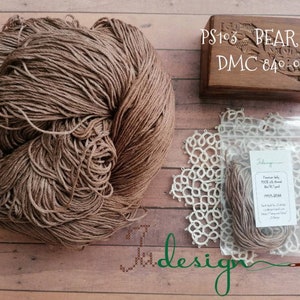 Puede incluir: Una madeja de hilo de seda marrón etiquetada "PS103 - BEAR silk DMC 840-988". El hilo está en una bolsa de plástico transparente con una etiqueta blanca que dice "Premium Baby Silk Thread DMC 840-988 BEAR".