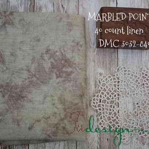 May include: A folded piece of marbled linen fabric in shades of beige and brown, with a delicate white lace doily and a small wooden box. The box is engraved with the words "MARBLED POINTER" and "4° count linen DMC 3032-84°".