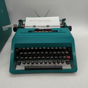 1969 teal Olivetti Studio 45 portable typewriter with owner&#39;s manual, case, and key