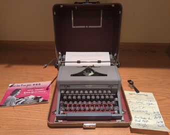 1950 Gray Royal Arrow portable manual typewriter with carrying case, owner's manual, key, cleaning brush, and original sales receipt