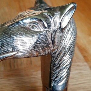 May include: A silver horse head walking stick with a wooden shaft. The horse head is detailed and realistic.