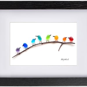 May include: A framed art print featuring a row of colorful birds perched on a branch. The birds are in shades of purple, blue, teal, green, orange, and red. The artwork is set against a white background and framed in black.