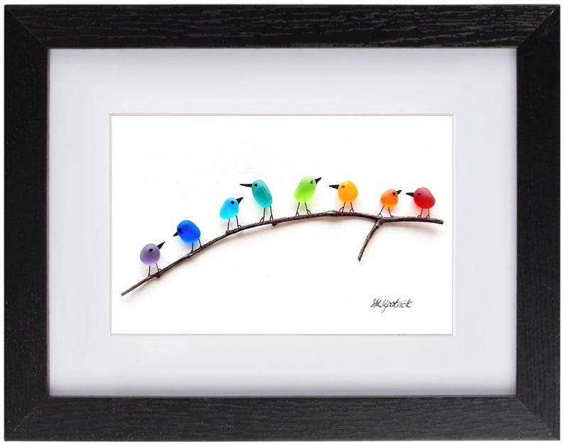 May include: A framed art print featuring a row of colorful birds perched on a branch. The birds are in shades of purple, blue, teal, green, orange, and red. The artwork is set against a white background and framed in black.